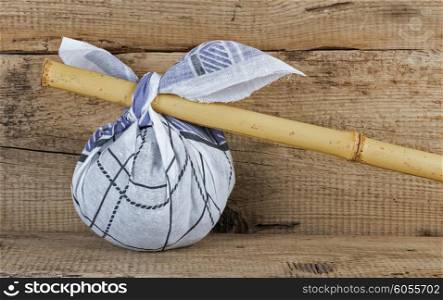 Rural knapsack on a bamboo pole on a old wooden background