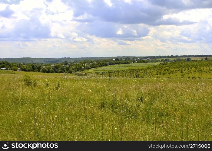 Rural landscape. Meadow, garden and village in the summer period