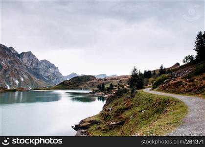 Rural landscape scenery with hiking trail with pine tree along Trubsee lake on the Swiss alps, foot of mount Titlis of Engelberg