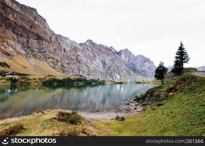 Rural landscape scenery with small cottage on Trubsee lake shore, Swiss alps Mount Graustock peak on background, foot of mount Titlis in Engelberg