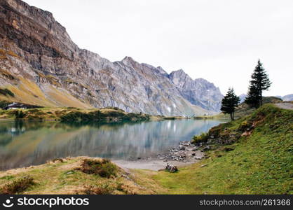 Rural landscape scenery with small cottage on Trubsee lake shore, Swiss alps Mount Graustock peak on background, foot of mount Titlis in Engelberg