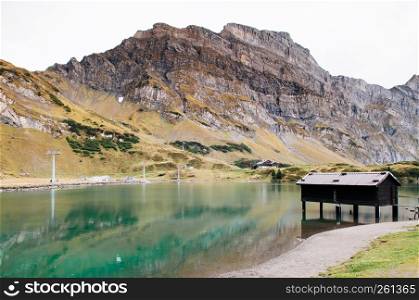 Rural landscape scenery with small lake cottage on Trubsee lake shore, Swiss alps Mount Graustock peak on background, foot of mount Titlis in Engelberg