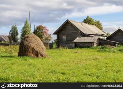 Rural landscape with old log house and haystack in the vegetable garden, Vologda region, Russia