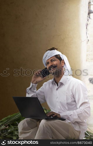 Rural man talking on phone while working on laptop