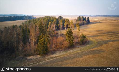 Rural panorama of spring agriculture fields and wood. Beginning of gardening season, picturesque aerial view. Sunny March-April evening scene. Calm spring countryside sunset. Belarus, Minsk region