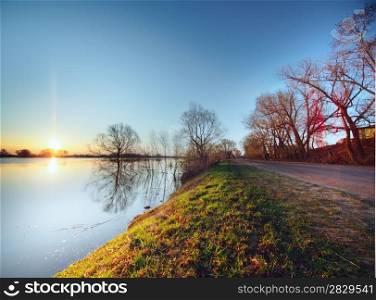 Rural road on sunrise. Road near water. Hight water at Oka river in Russia
