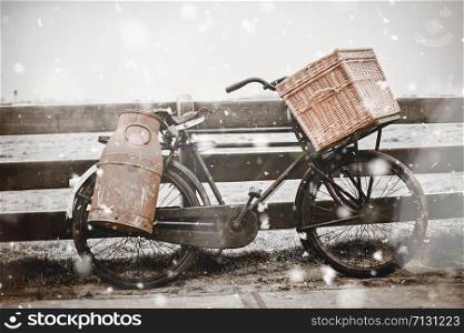 Rural winter landscape with old rusty bicycle with can and basket. Retro Pastel trendy toning. Beautiful inspiring moody faded scenery