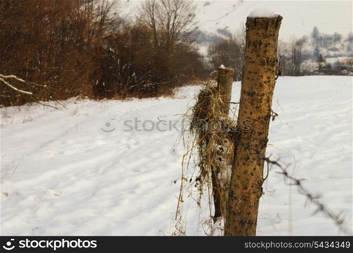 Rural winter mountain landscape with fence and road under the snow.