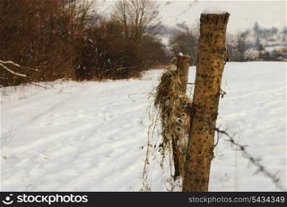Rural winter mountain landscape with fence and road under the snow.
