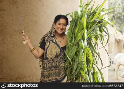 Rural woman holding bunch of crops and sickle