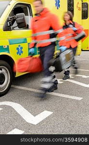 Rushing blurry paramedic team with portable devices and ambulance car