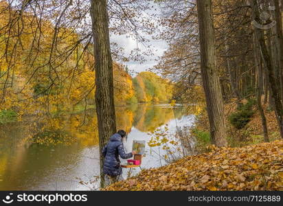 Russia, Moscow region October 05, 2019 Astfievo estate, a beautiful view of the lake in autumn, surrounded by yellowed trees, the photo also shows the landscape worker. beautiful pond in the park