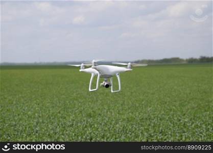 Russia, Poltavskaya village - May 1, 2016  Flying white quadrocopters DJI Phantom 4 over a field of wheat. Flying gadget for video.. Flying white quadrocopters over a field of wheat
