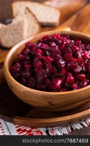 Russian beetroot salad in wooden bowl with rye bread, rustic, close up, selective focus