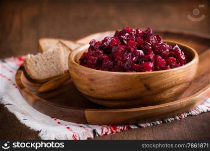 Russian beetroot salad in wooden bowl with rye bread, rustic, selective focus