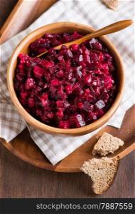 Russian beetroot salad in wooden bowl with rye bread, rustic, selective focus, top view