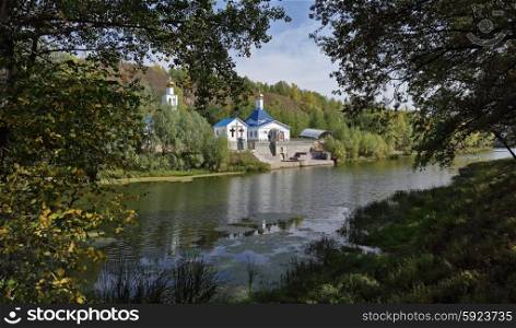 Russian Orthodox Church on the shore of a pond in autumn