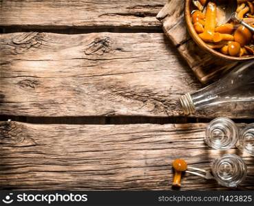 Russian style. Vodka with pickled mushrooms. On wooden background.. Russian style. Vodka with pickled mushrooms.