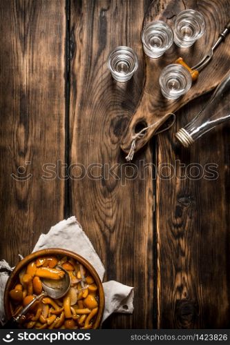 Russian style. Vodka with pickled mushrooms. On wooden background.. Russian style. Vodka with pickled mushrooms.