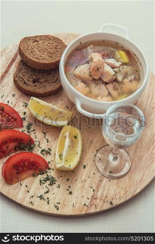 Russian traditional fish soup - ukha, served with bread lemon tomato and vodka. Russian traditional fish soup