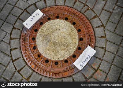 Rust metal manhole cover on sidewalk