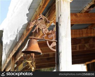 Rusted bell on side post of shed.