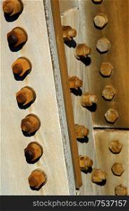 Rusted nuts and bolts affixed on building.
