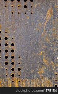 rusted, originally black colored, metal with circular holes