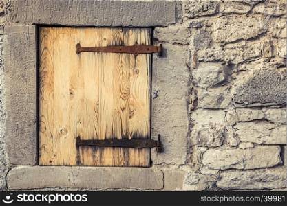 Rustic architecture background with a stone wall of a german house, with it's wooden trap door and the rusty hinges