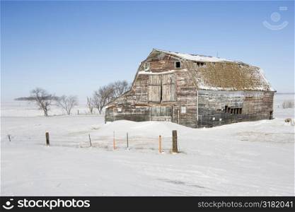 Rustic barn in rural snow covered landscape.