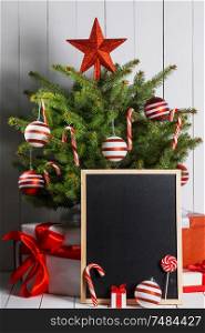 Rustic chalkboard and christmas tree decorated with candy canes and baubles. Christmas tree with chalkboard