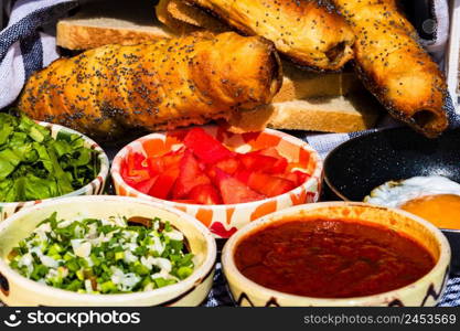 Rustic composition with sausages rolls and different bowls with sauce and chopped vegetables ( tomatoes, green lettuce, green onion, green garlic)