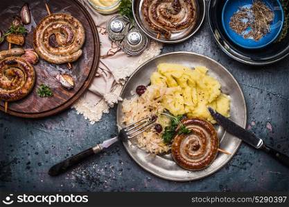 Rustic food with roasted sausage mashed potatoes and sour cabbage salad, served in plate with cutlery, top view. German food concept