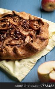 Rustic galette with crispy apple slices and pecan nuts. Autumnal specific apple pie on a wooden table