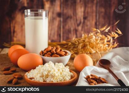 Rustic homemade protein balanced diet food. Cottage cheese, eggs, nuts and milk on a wooden background.. Rustic protein balanced diet food. Cottage cheese, eggs, nuts and milk on a wooden background.