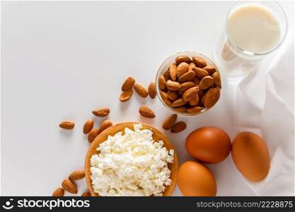 Rustic homemade protein balanced diet food. Cottage cheese, eggs, nuts and milk on a white background.. Protein food on a white background - cottage cheese, eggs, nuts. A set of healthy foods for a balanced diet.
