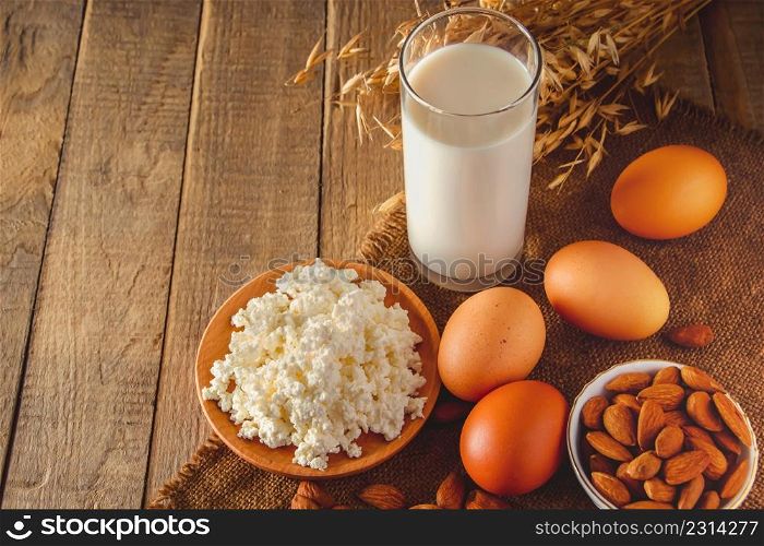 Rustic homemade protein balanced diet food. Cottage cheese, eggs, nuts and milk on a wooden background. Place for text. Rustic protein balanced diet food. Cottage cheese, eggs, nuts and milk on a wooden background.