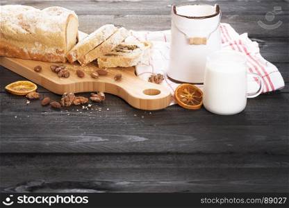 Rustic image with homemade sponge cake, with poppy seed, walnuts and almonds, and a cup of milk, on a vintage wooden table, in the morning light.