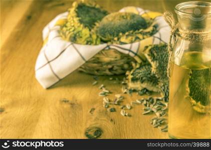 Rustic image with sunflower oil and a wooden basket full with sunflower plants and seeds