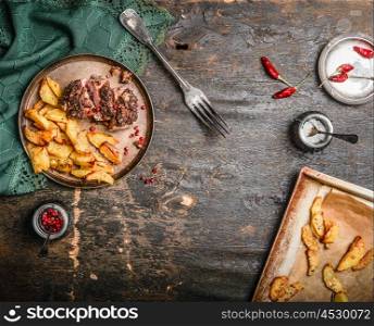 Rustic Kitchen table served with Pork fillet with a crust and baked potato in plate with fork, top view, frame