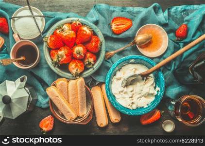 Rustic kitchen table with strawberry tiramisu cooking ingredients, top view. Italian food concept