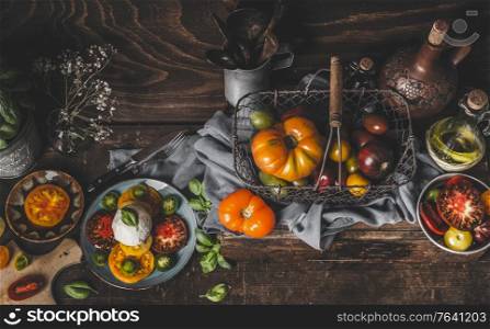 Rustic mediterran food concept with fresh harvested colorful tomatoes and mozzarella. Homemade Caprese. Seasonal food on wooden background. Top view