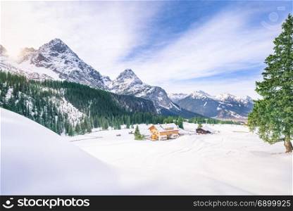 Rustic scenery with wooden houses surrounded by the snowy Alps mountains, the green fir forests and a thick layer of snow, in Ehrwald, Austria