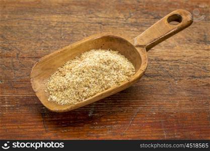 rustic scoop of golden flax seed meal against grunge wood table