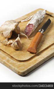 Rustic still life with cutting board, smoked sausage, garlic and folding knife