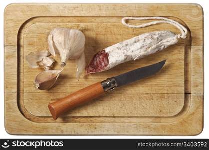 Rustic still life with cutting board, smoked sausage, garlic and folding knife