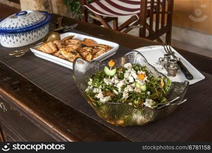 Rustic table with dishes of grilled salmon, salad and sauteed potatoes