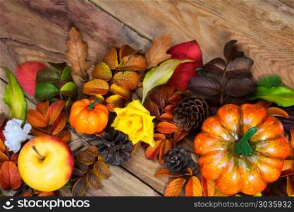 Rustic Thanksgiving colorfull fall leaves wreath. Thanksgiving orange pumpkins, apple, pine cones and colorfull fall leaves wreath on the wooden background, top view