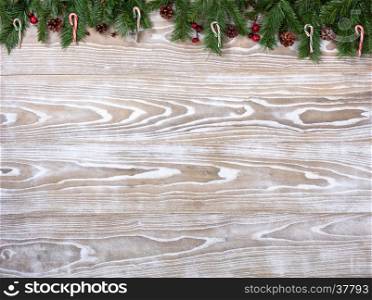 Rustic white wooden background for Christmas concept with fir branches, candy canes and pine cones. Overhead view with copy space.