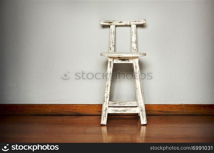 Rustic white wooden stool against a plain wall background